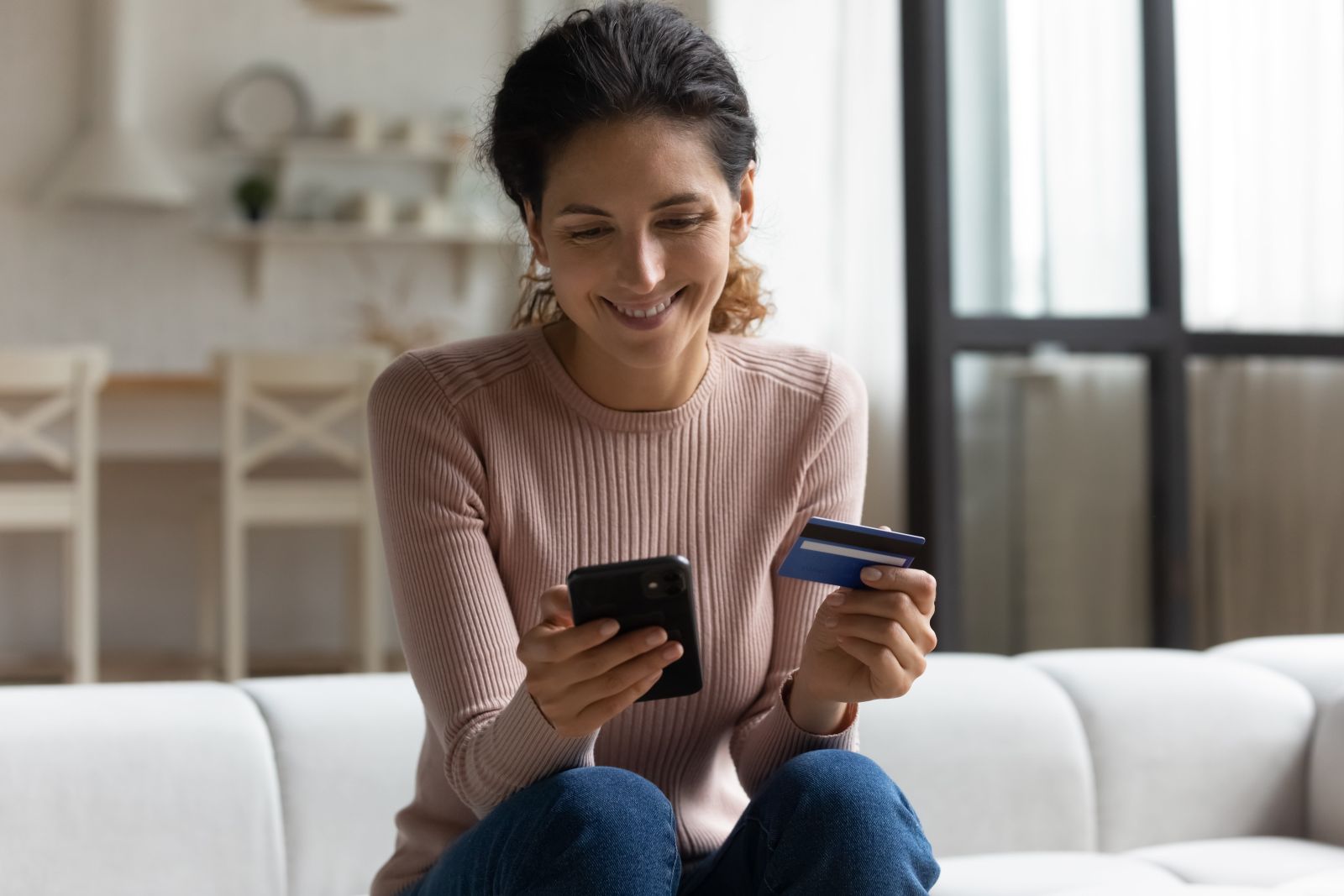 Uśmiechnięta kobieta dokonująca płatności kartą za zakupy online